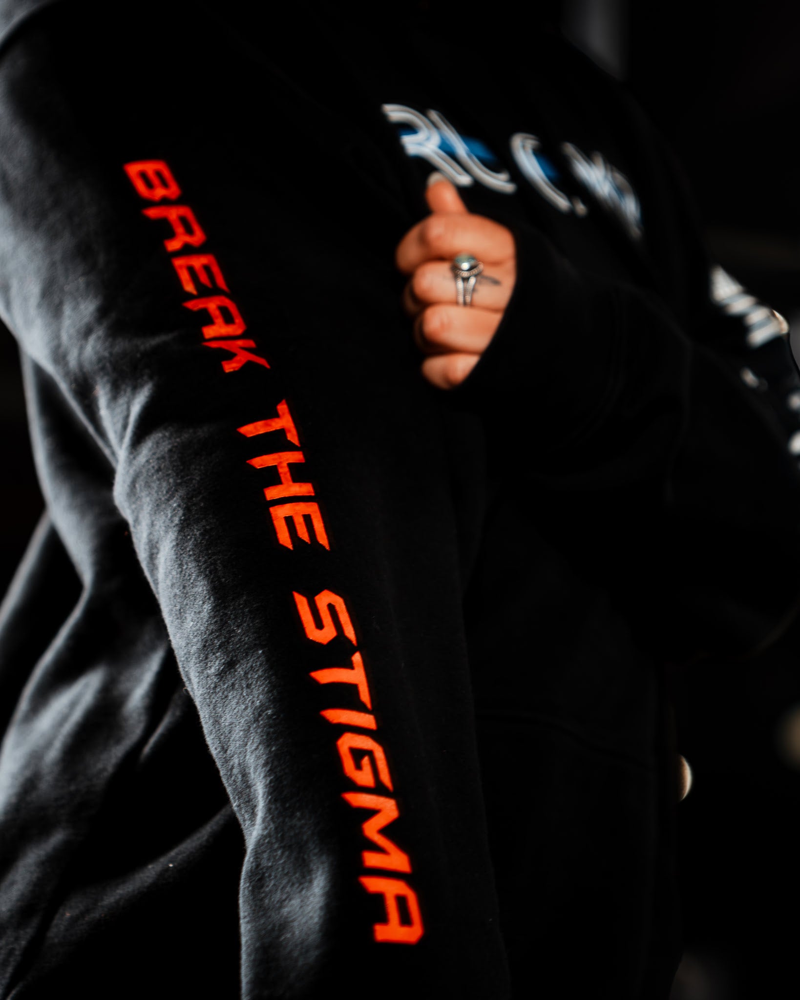 Black shirt with orange text 'Break The Stigma' on sleeves.