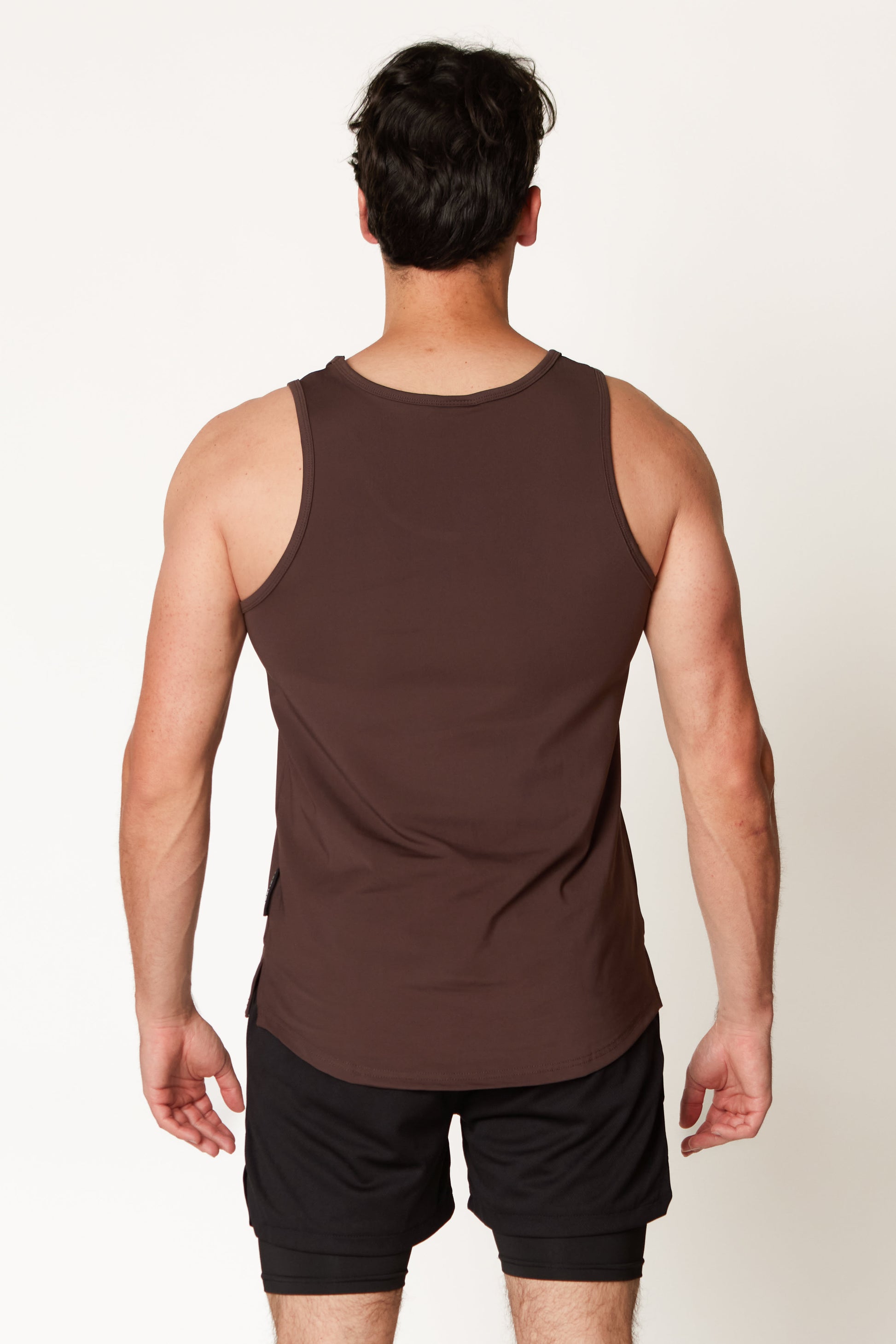 Man wearing a brown tank top and black shorts on a white background