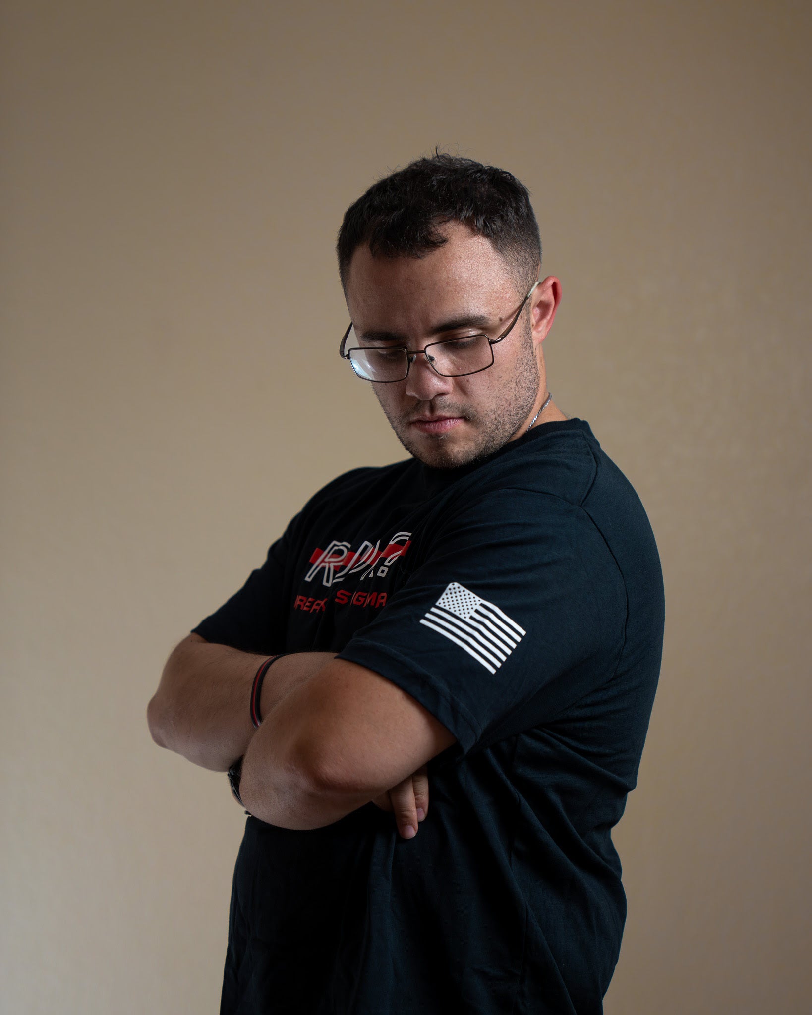 Man wearing a black t-shirt with logos against a beige background
