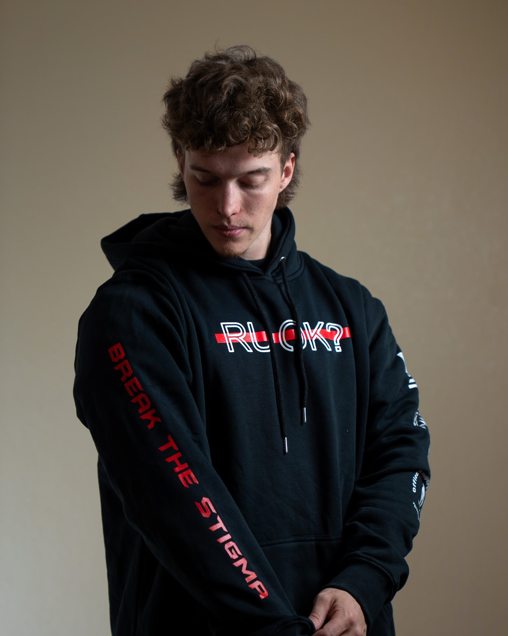 Person wearing a black hoodie with visible branding against a beige background