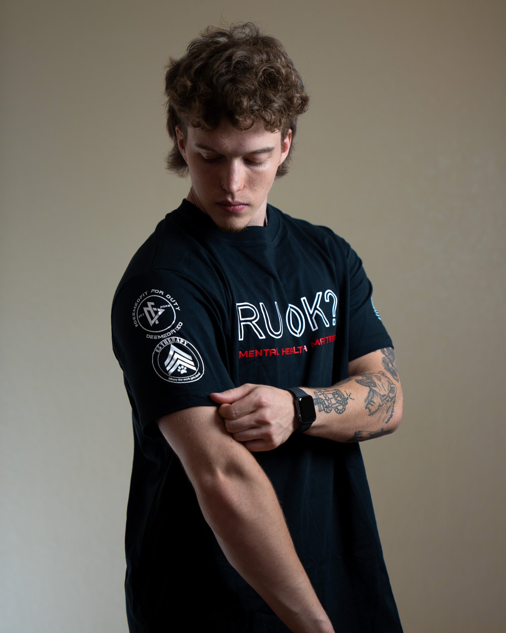 Person wearing a black t-shirt with visible branding on a plain background