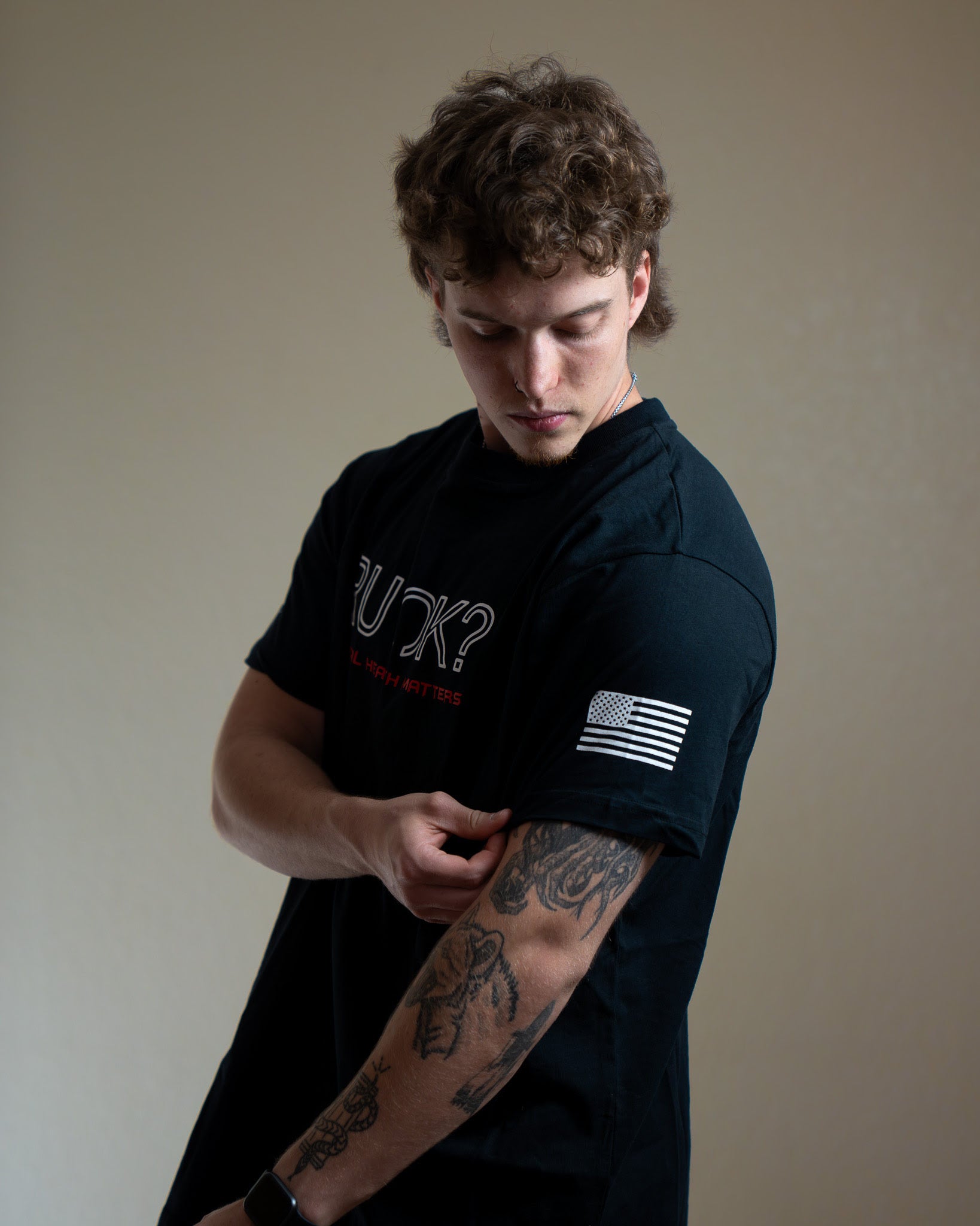 Man wearing a black t-shirt with text and a flag design on a plain background