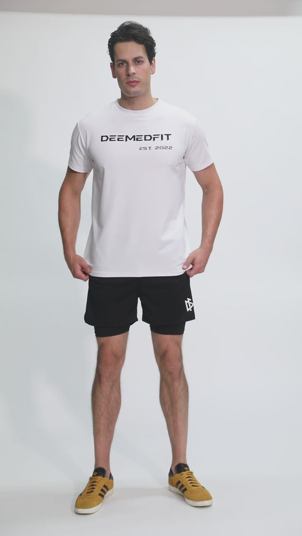 Male model stretching in DeemedFit’s white Compellence performance tee for men.