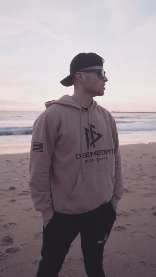 tan hoodie highlighting the American flag patch on the left sleeve.